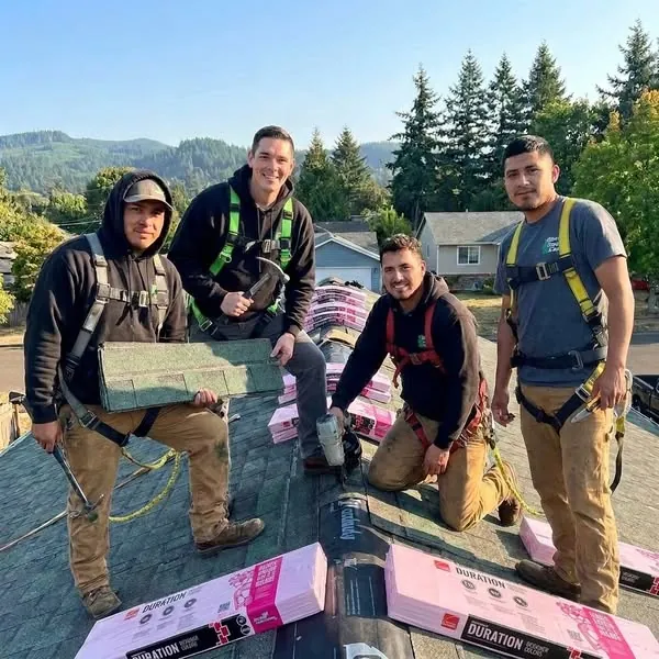 Four Bonn Roof Care roofers in safety harnesses smiling on a roof during a shingle installation.