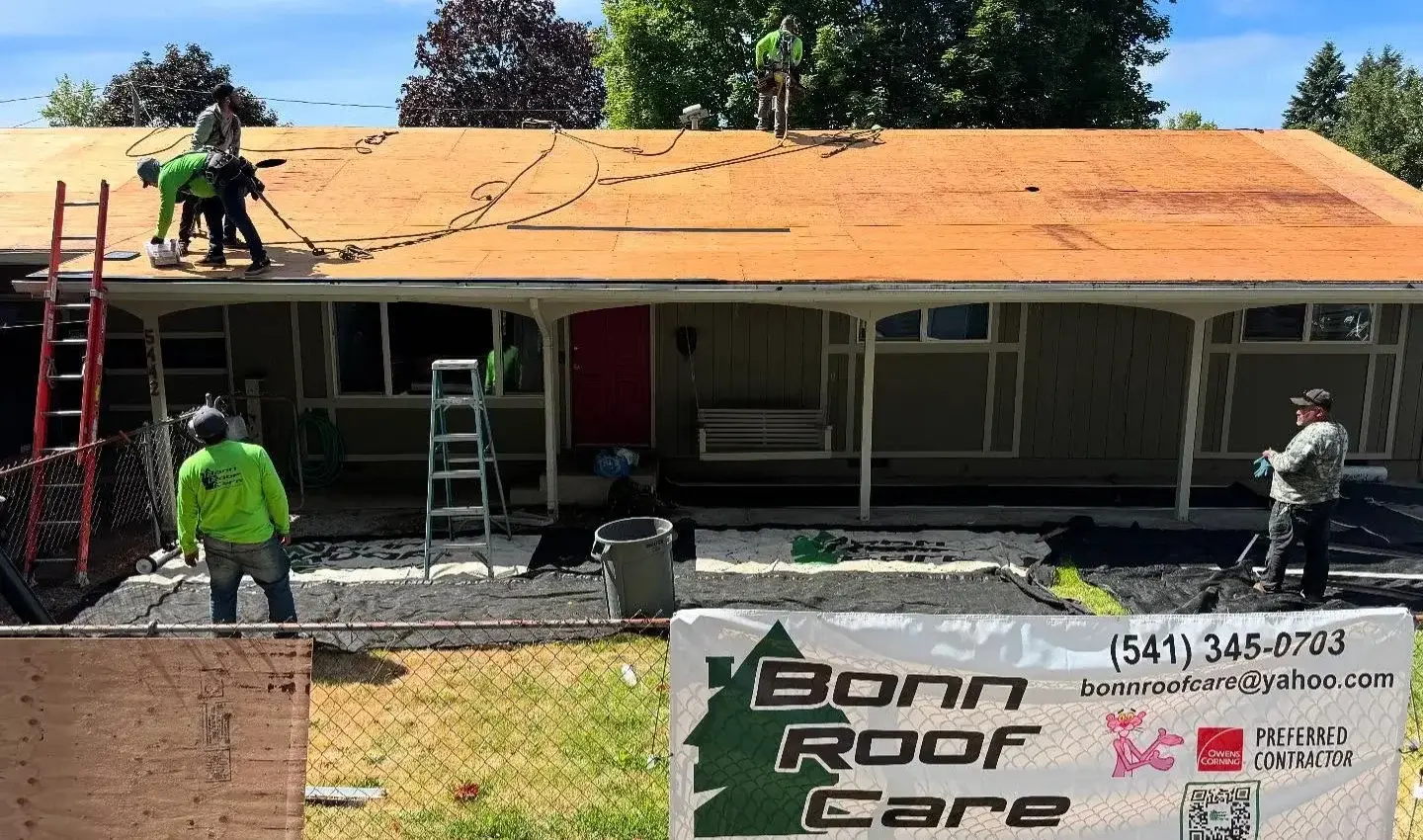 Bonn Roof Care crew re-decking a Eugene home with tarps laid over the yard and landscaping below